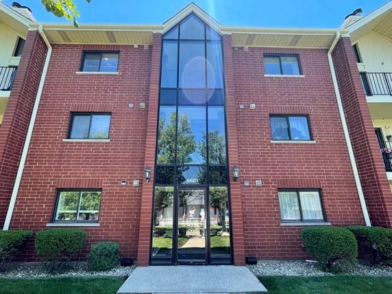 Front view of a three-story brick building with large central glass windows.