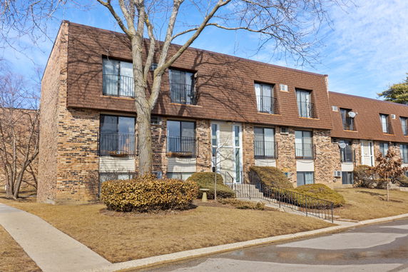 Front view of a two-story building with brick exterior and brown shingles.