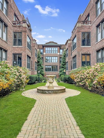 Front view of a multi-story brick building with large windows and a central walkway.