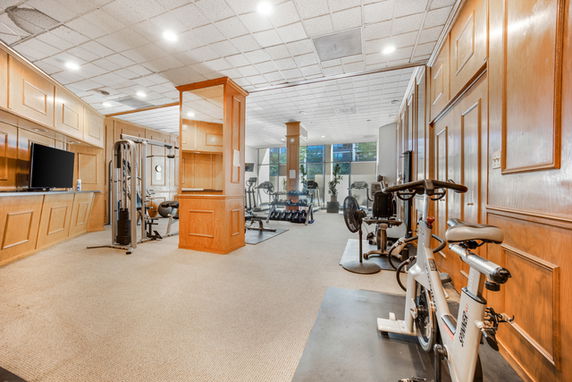 Indoor gym area with exercise equipment and wood panel walls.