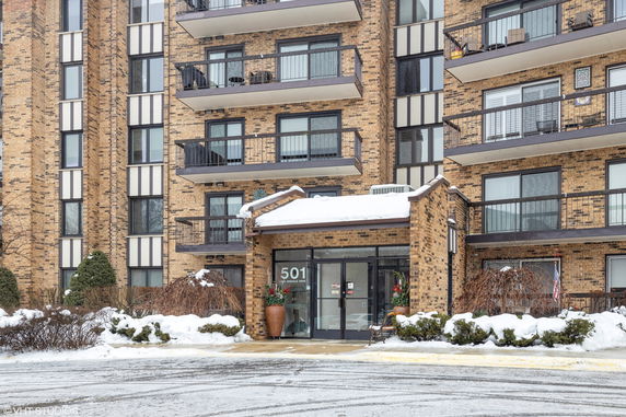 Front view of a multi-story brick building with balconies and a glass entrance.