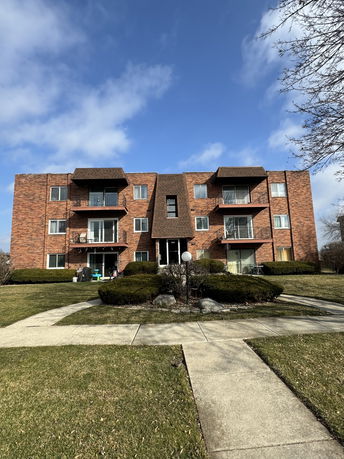 Front view of a multi-story brick apartment building with balconies.