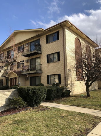 Front view of a brick apartment building with balconies.
