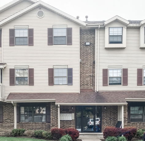 Front view of a three-story residential building with brick and siding exterior.
