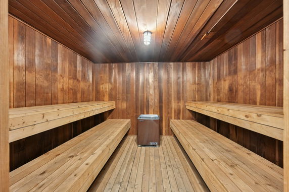 Interior view of a wooden sauna room with benches and a heater.