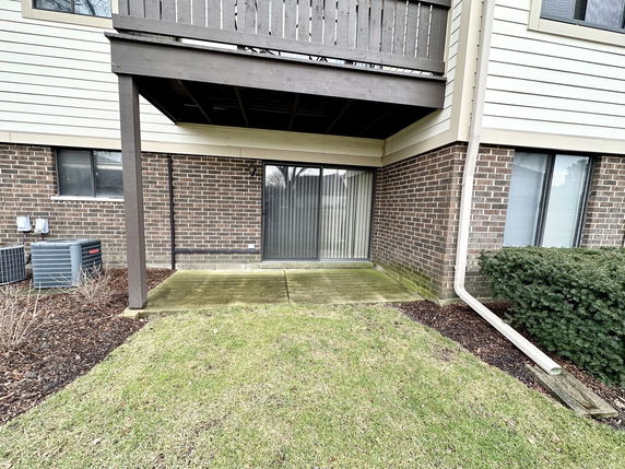 Rear view of a building with a brick exterior and a covered patio area.