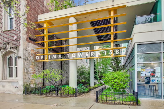 Front view of a building entrance with modern architectural design, featuring yellow horizontal beams and glass elements.