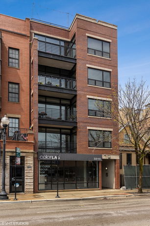 Front view of a multi-story brick building with balconies and a storefront.