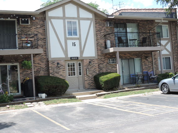 Front view of a two-story apartment building with balconies and a brick exterior.