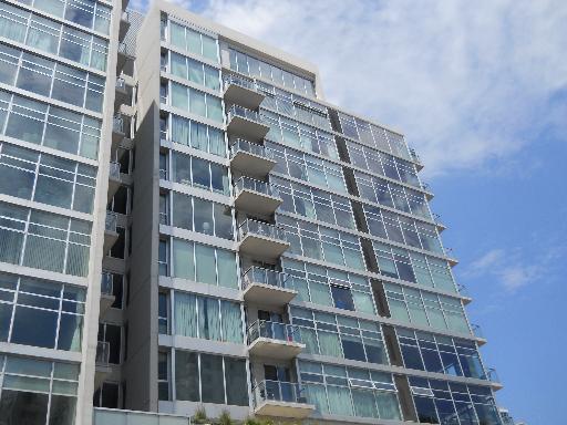 Front view of a multi-story apartment building with large windows and balconies.