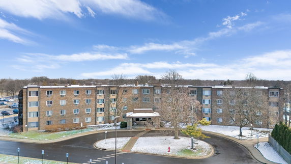 Front view of a multi-story brick apartment building with a covered entrance.