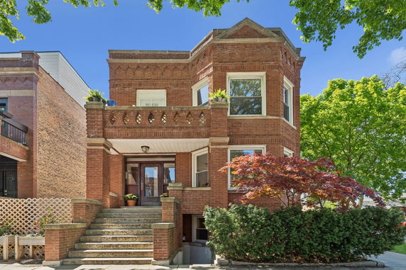 Front view of a two-story brick house with a decorative front staircase.