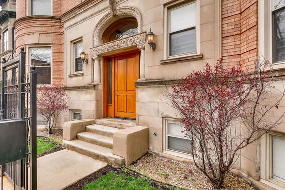 Front view of a residential building with an ornate arched entryway and wooden double doors.