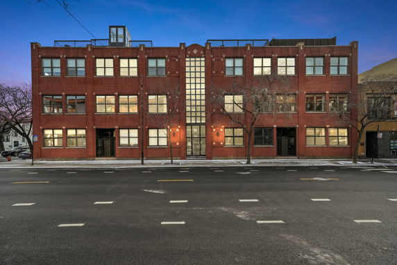 Front view of a red brick multi-story building with large windows.