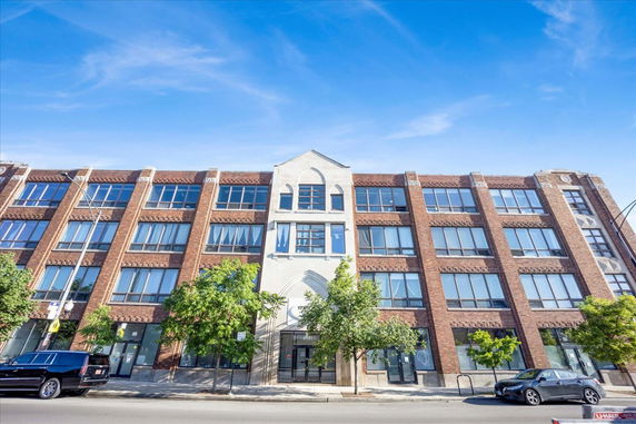 Front view of a four-story brick building with large windows.