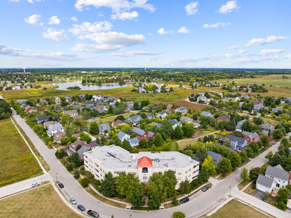 Wide-angle view of residential area with a large building in the foreground and houses spread out across the landscape.