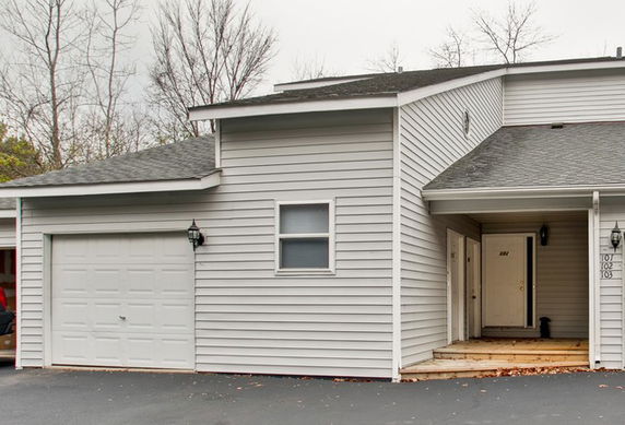 Front view of a two-story house with a garage and a small entry porch.
