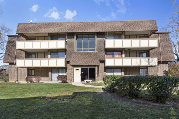 Front view of a three-story apartment building with multiple balconies and a brown facade.