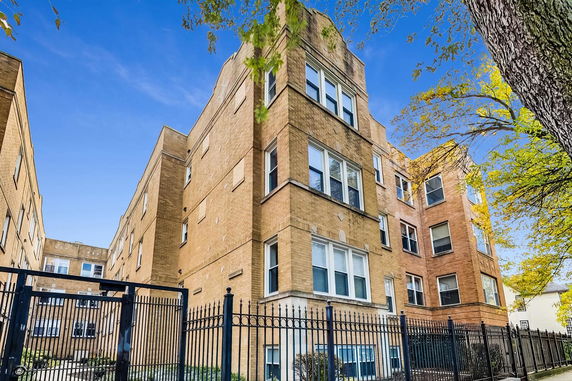Front view of a multi-story brick building with a gated entrance.