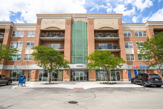 Front view of a multi-story commercial building with retail spaces and large windows.