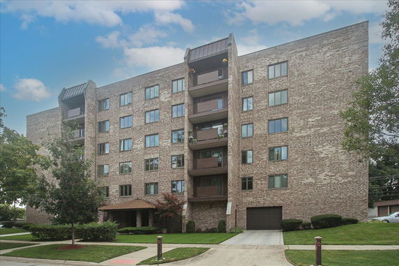 Front view of a multi-story brick apartment building with balconies.