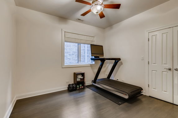 Room with a treadmill and a small rack of dumbbells.