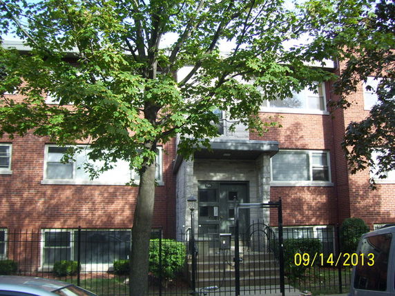 Front view of a brick residential building with a central entrance and multiple windows.