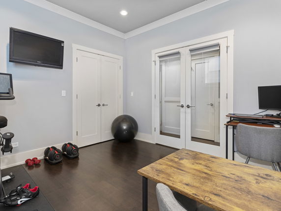 Indoor gym area with exercise equipment, desk, and television.