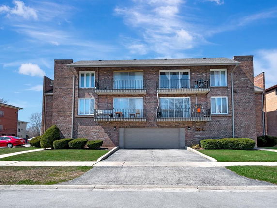 Front view of a two-story brick building with balconies and a garage.