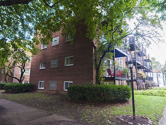 Front view of a brick multi-story apartment building with balconies.