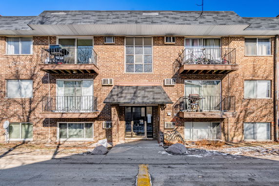 Front view of a three-story brick building with balconies and central entrance.