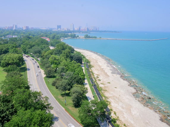 Panoramic view of a coastline with a road and city skyline in the distance.