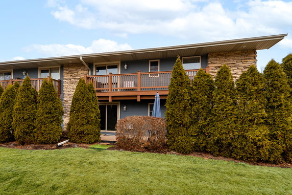 Front view of a two-story house with a balcony and stone facade.