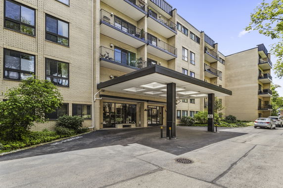 Front view of a multi-story apartment building with a covered entrance.