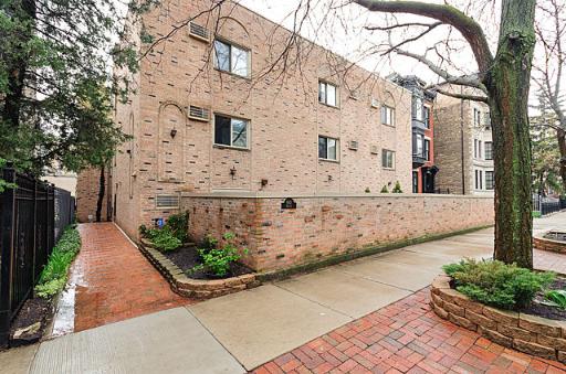 Front view of a brick apartment building with small windows and a brick wall.