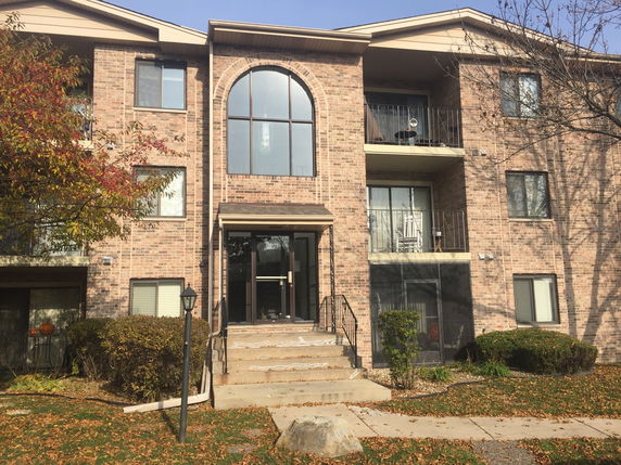 Front view of a multi-story brick building with balconies and a central entrance.