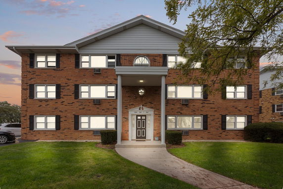 Front view of a multi-story brick building with large windows and a central entrance.