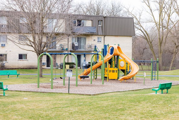 Outdoor play area with playground equipment near a residential building.