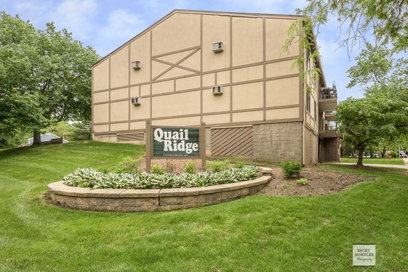 Side view of a multi-story condominium building with a sign reading 'Quail Ridge.'