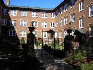 Front view of a multi-story brick building with a gated entrance.