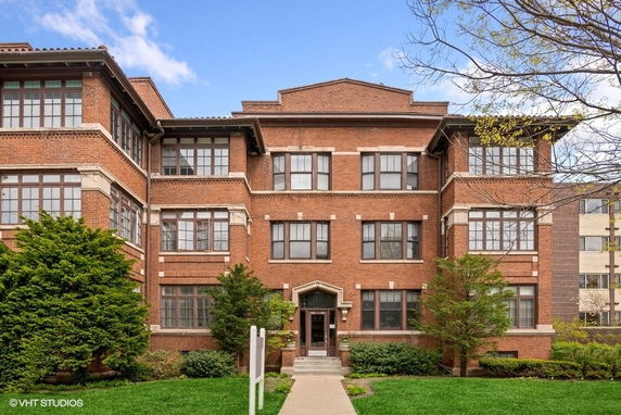 Front view of a three-story brick building with large windows and a central entrance.