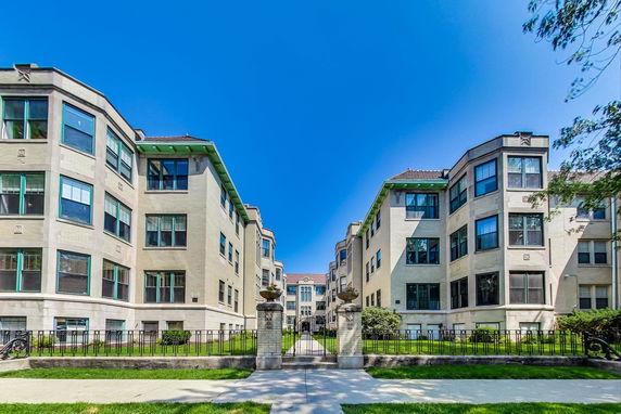 Front view of a multi-story apartment building with large windows and a central walkway.