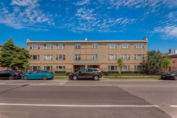 Front view of a three-story apartment building with a brick facade.