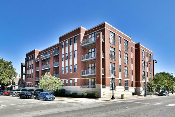 Front view of a multi-story brick apartment building with balconies.