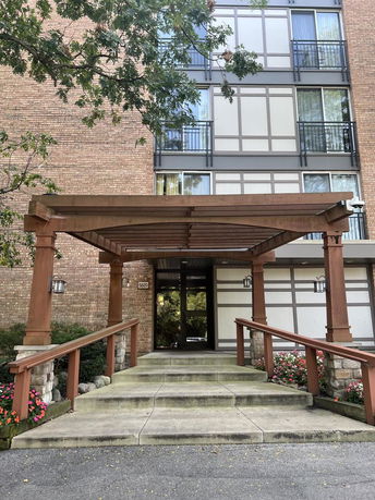 Front view of a multi-story building with a wooden pergola entrance.