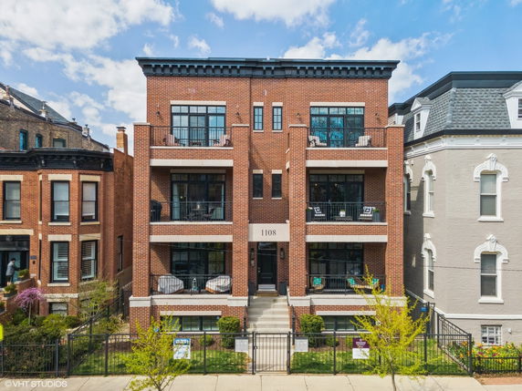 Front view of a four-story brick building with balconies and large windows.
