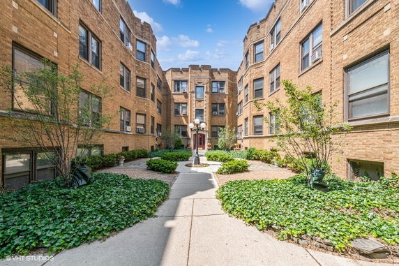 Front view of a multi-story brick apartment building with a courtyard.