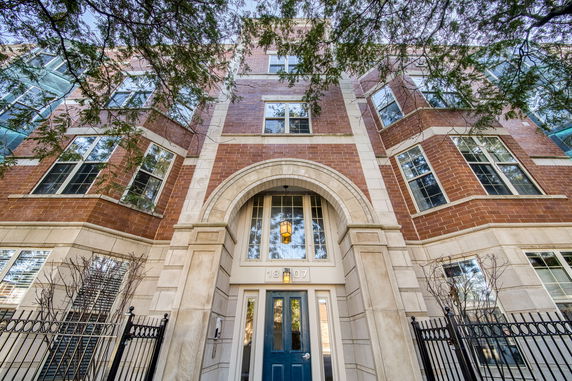 Front view of a multi-story building with brick facade and arched entrance.