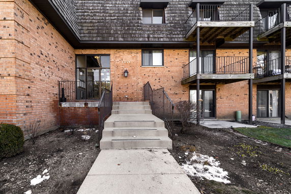 Front view of a multi-story brick building with balconies and a central staircase entrance.