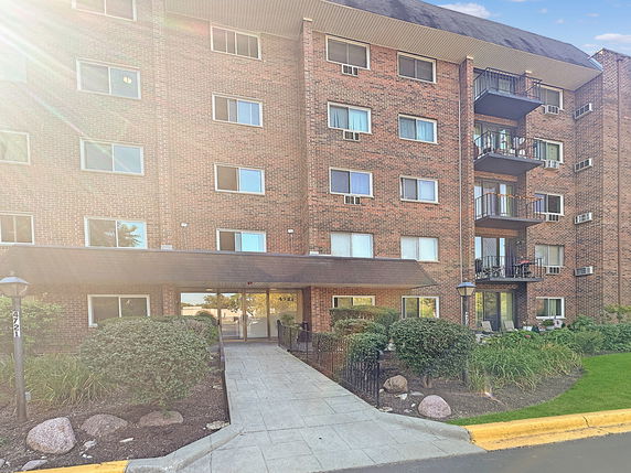 Front view of a multi-story brick apartment building with balconies.